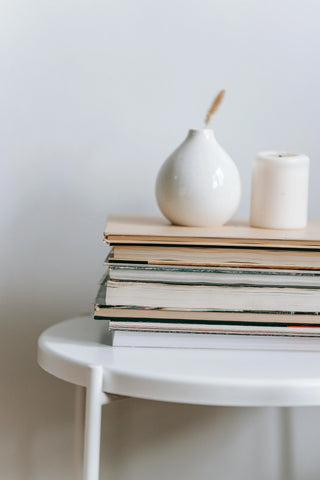 Books Stacked on White Stool with Vase on Top